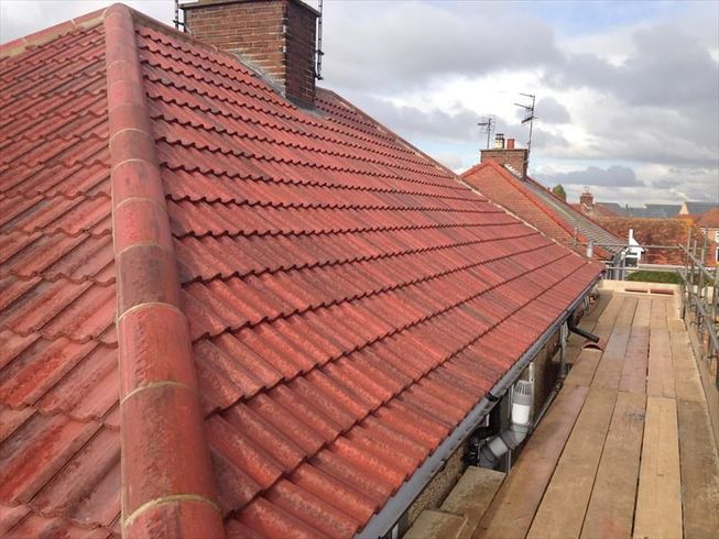 A red tiled roof with scaffolding, showing a need for professional roof repair in Bicester from an experienced roofer.