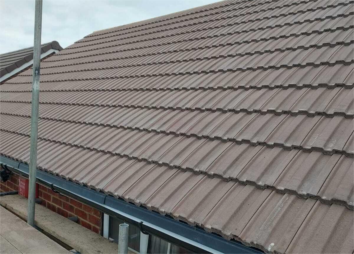 Brown tiled roof with guttering, brick wall visible.