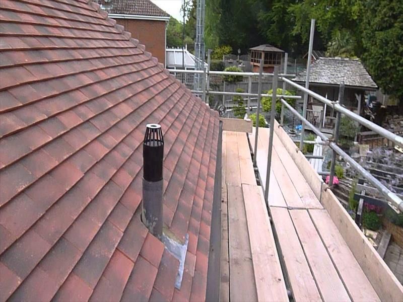 A roof with a chimney on it and a wooden scaffolding.