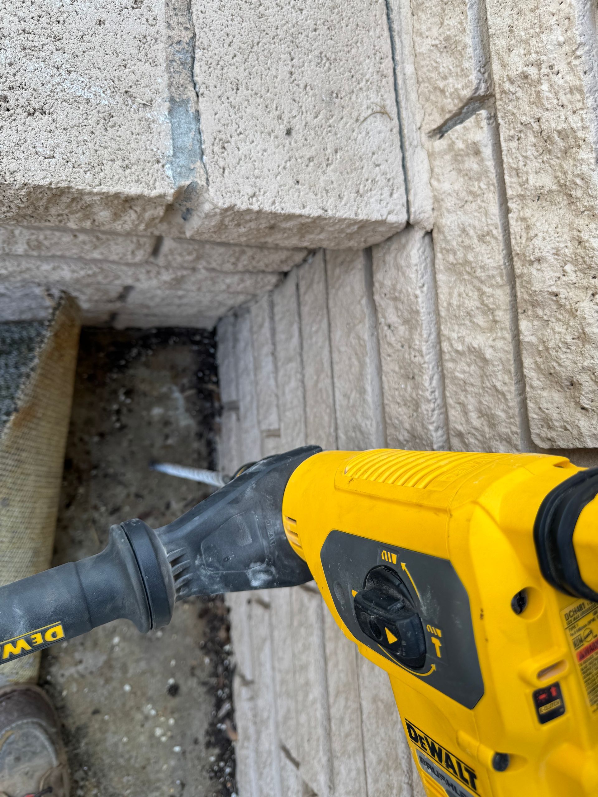 Yellow DeWalt demolition hammer breaking stone steps.
