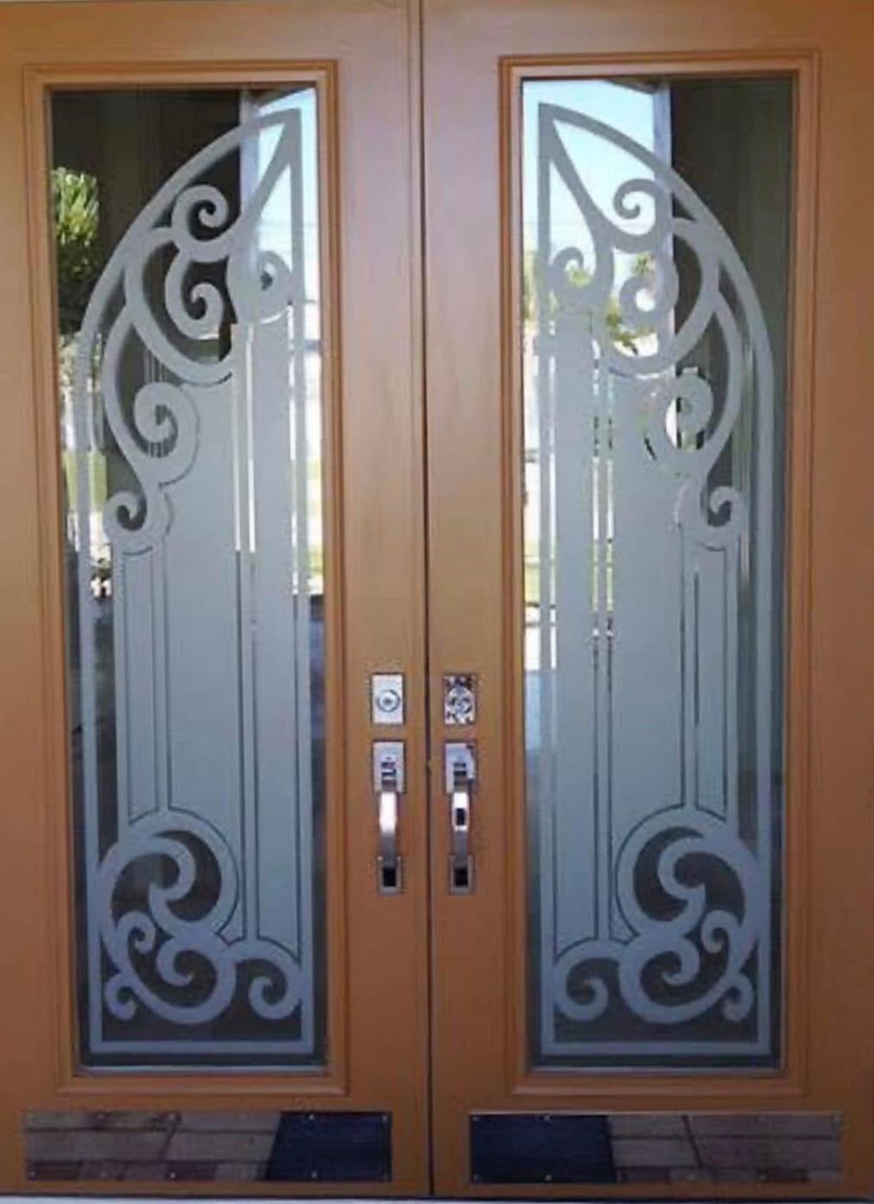 Wooden double doors with decorative frosted glass panels featuring swirling designs.