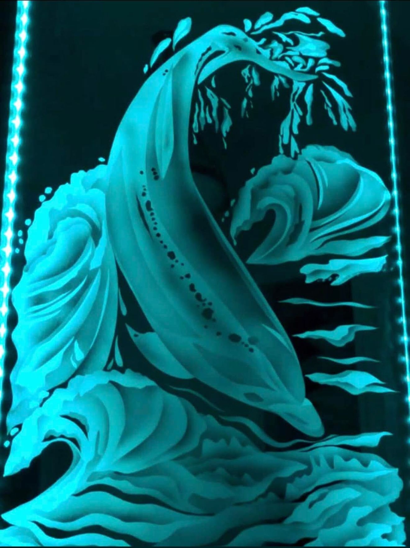 Etched glass art of a dolphin leaping through waves, turquoise glow.