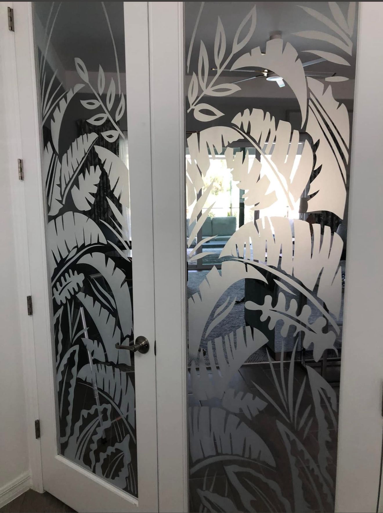 White French doors with etched tropical leaf design.