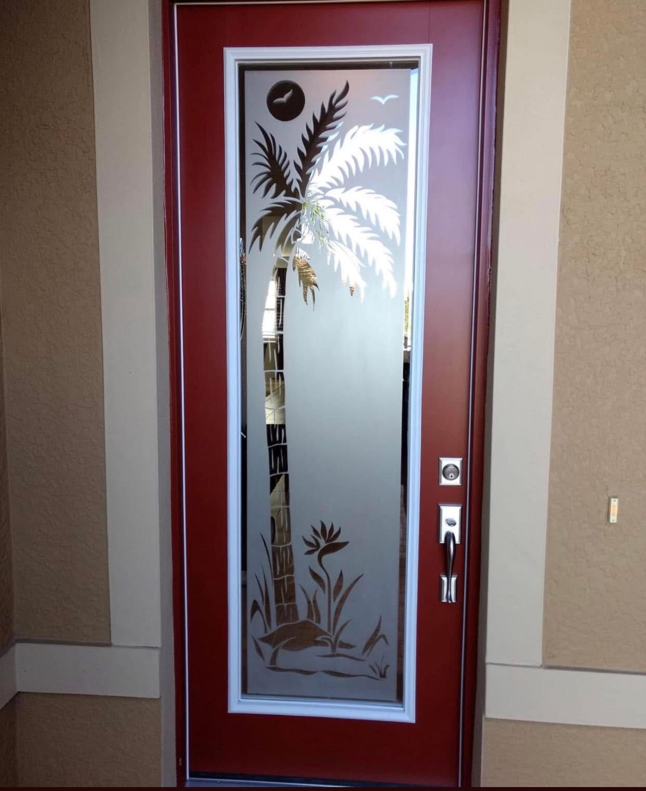 Red front door with frosted glass panel etched with a palm tree design.