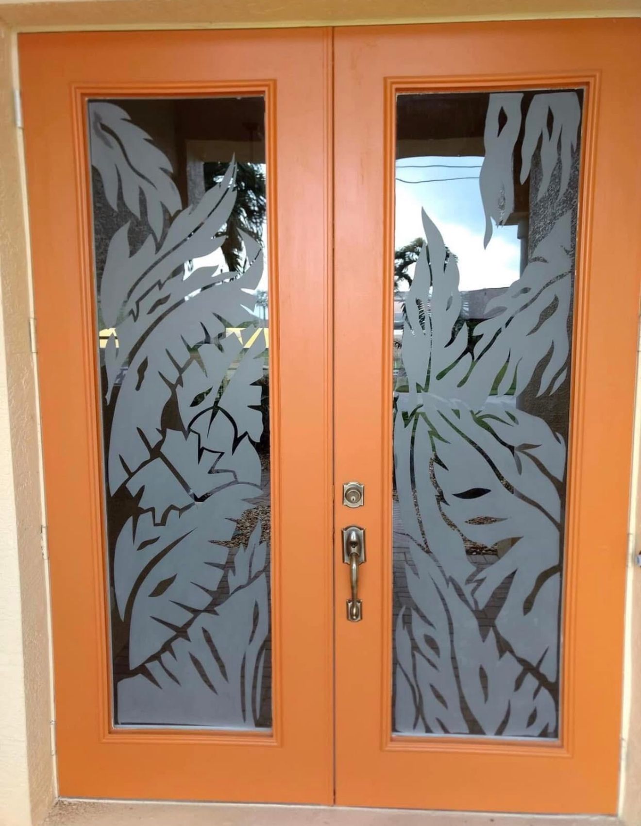 Orange double doors with frosted leaf design in glass panels.