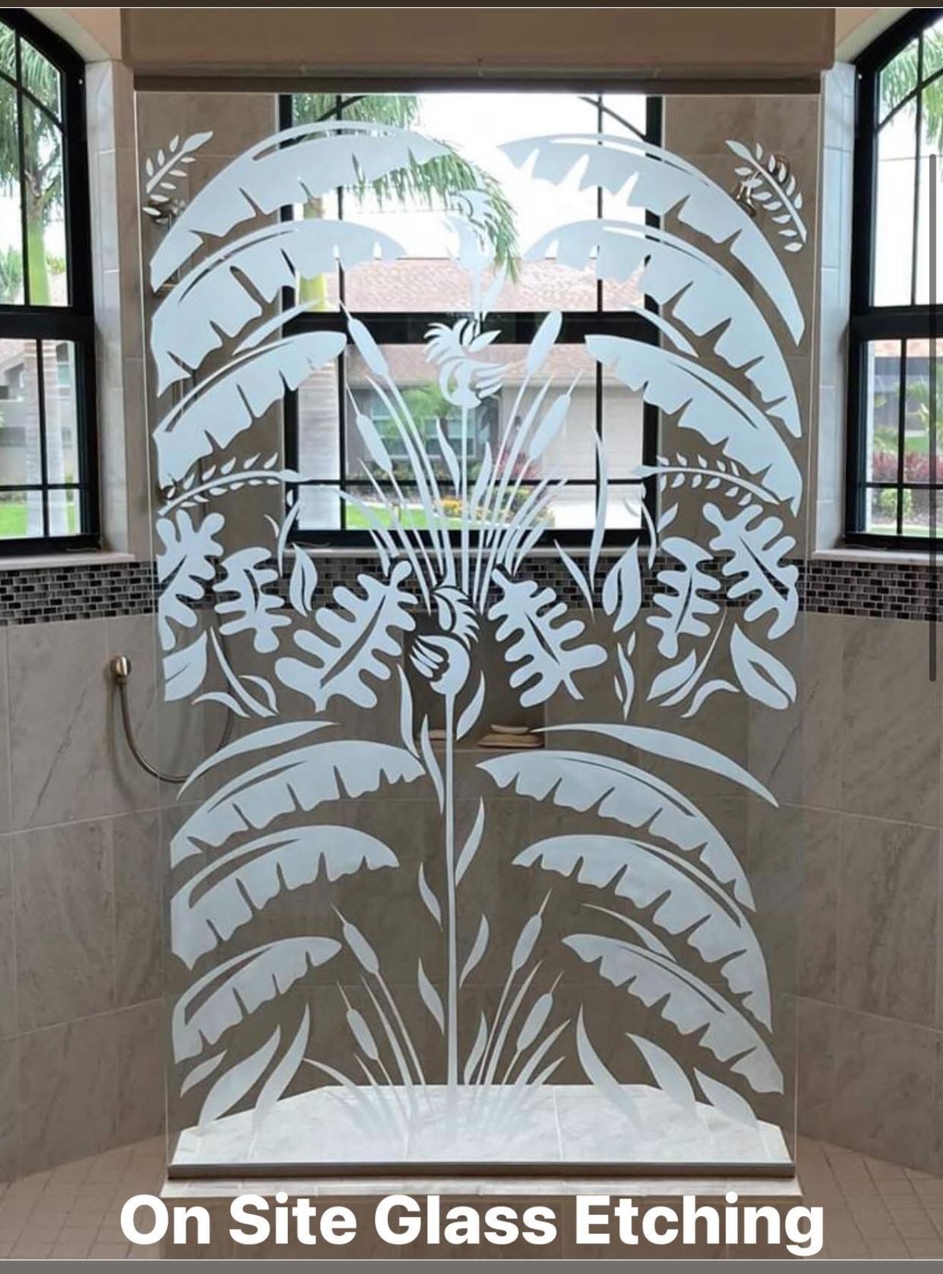 Etched glass shower door with tropical plant design, between windows.