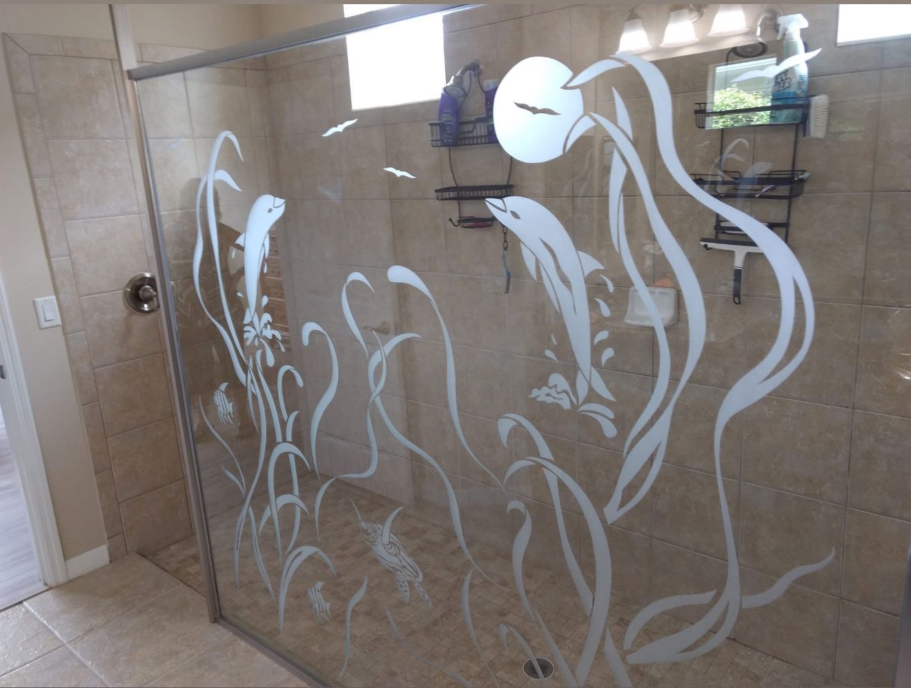 Shower with etched glass featuring dolphins and ocean plants.