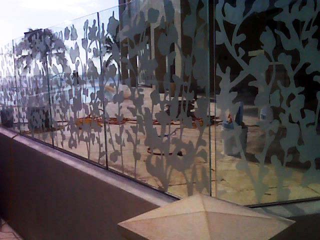 Glass railing with floral etched design, outdoors.