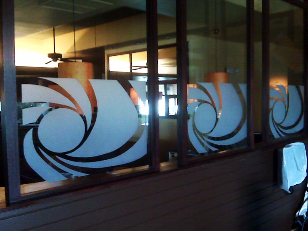Frosted glass panels with swirling designs in a restaurant setting. Brown frames and warm lighting.