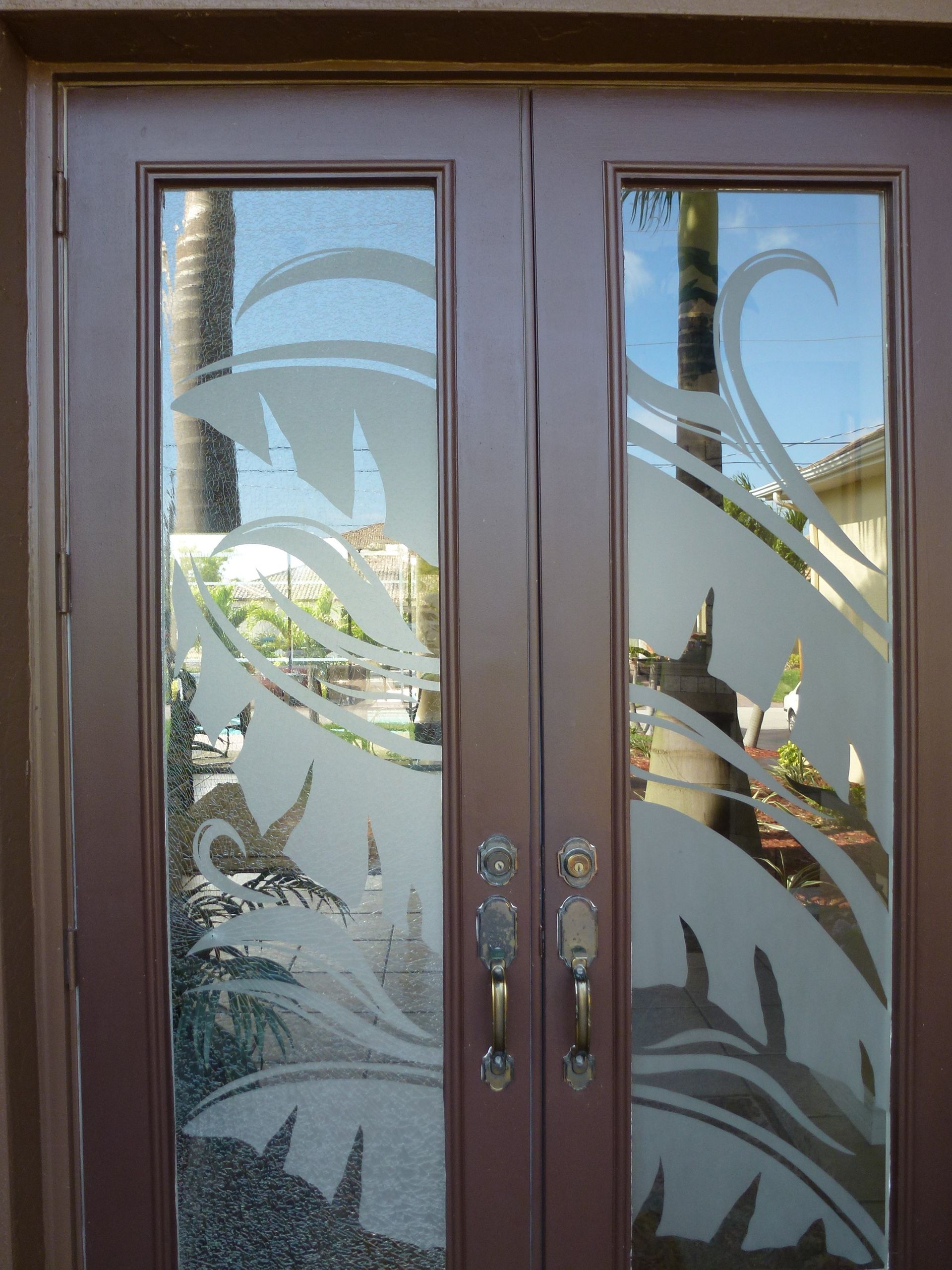 Double brown front doors with frosted glass design, decorative handles, outdoor setting, daytime.