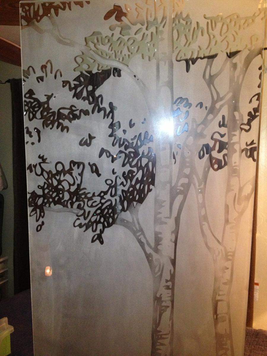 Etched glass screen with tree silhouettes in brown and gray, indoors.