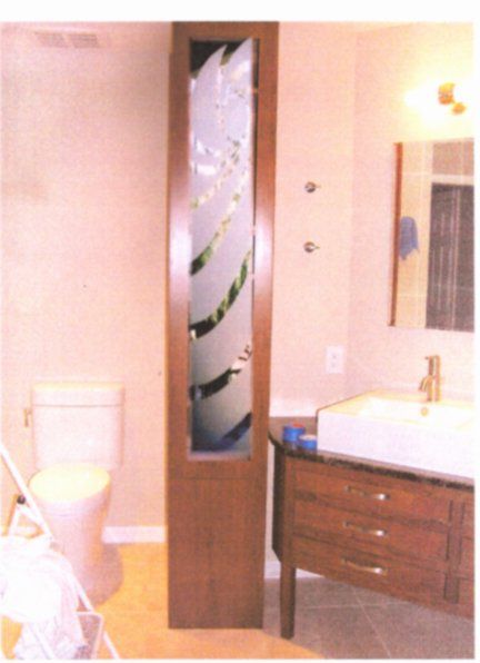 Bathroom with a tall, frosted glass and wood door, toilet, sink, and mirror.