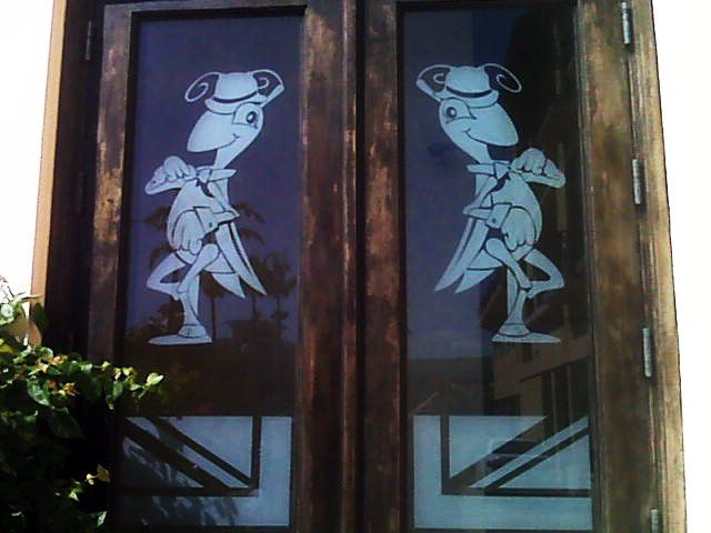 Wooden double doors with cartoon figures etched on the glass.