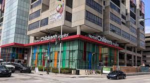 Norton Children's Hospital exterior: Modern building with red accents, colorful glass panels, and parked cars.