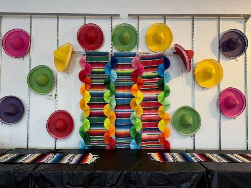 Wall decorated with colorful sombreros and serape fabric, for a festive celebration.