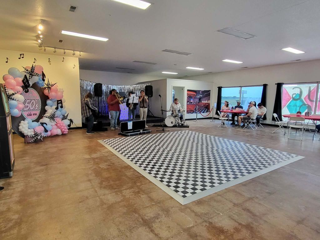 Party with band, balloons, checkered dance floor. Indoor setting.