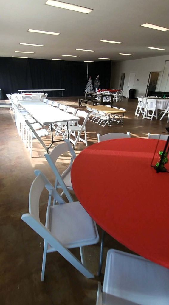 Event venue in Centerview MO with rows of tables, some with red cloths. White chairs are set up.