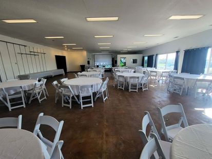 Event hall with people seated at tables, crafting and browsing various displays.