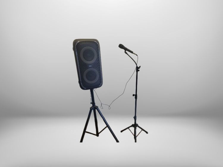 Black speaker and microphone on stand against a white wall.