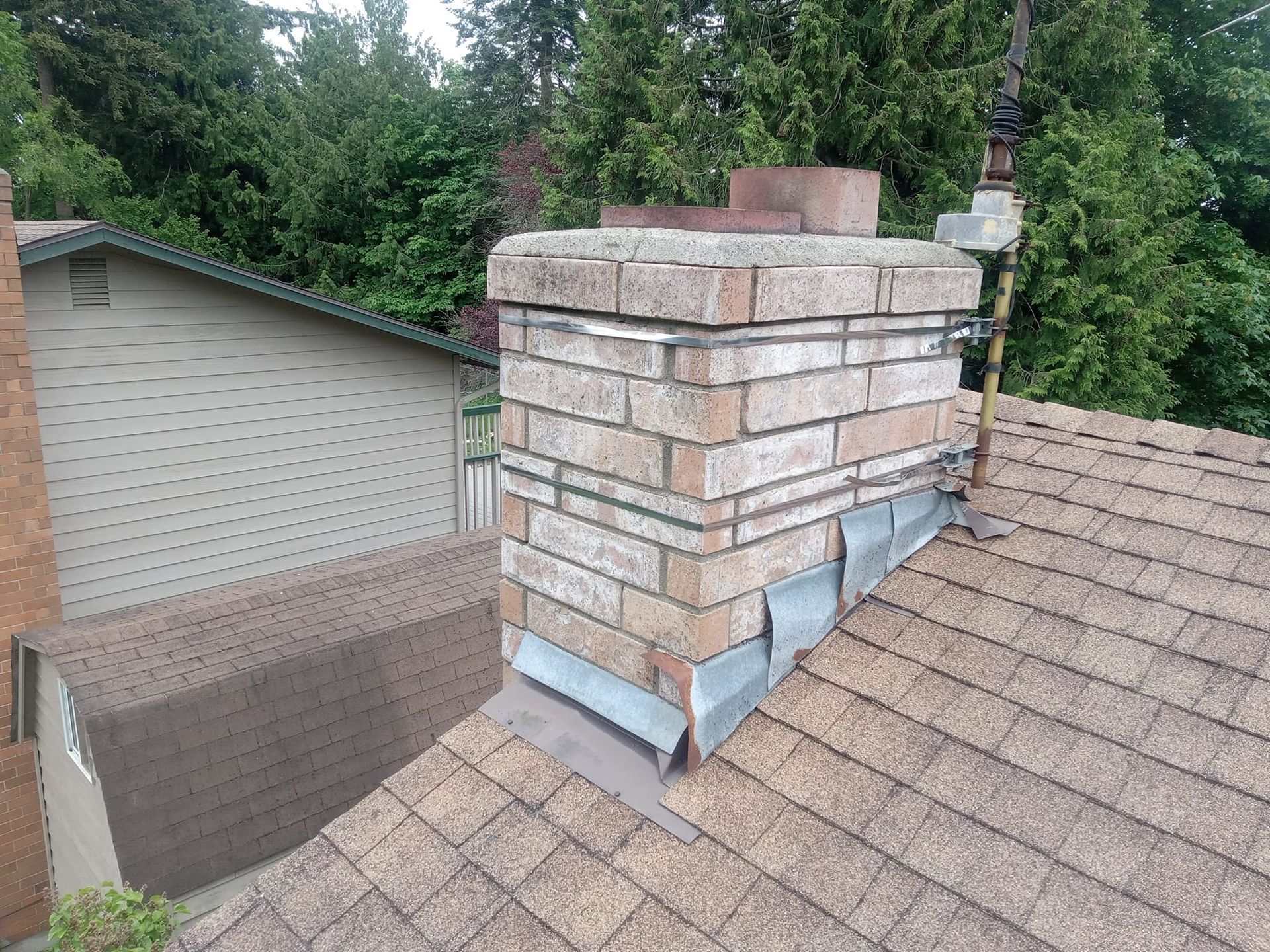 A brick chimney is on the roof of a house