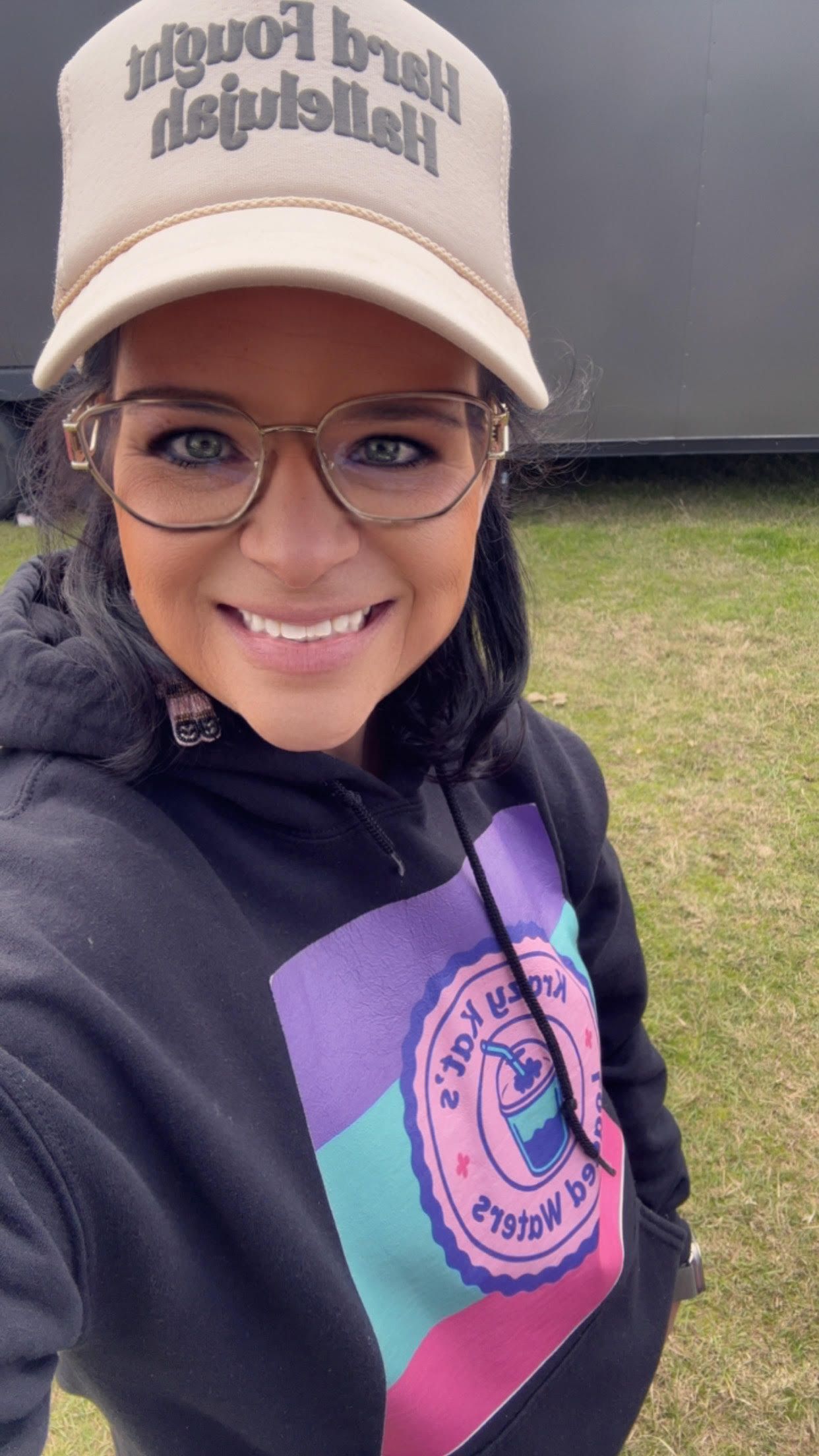 A vendor's table displays crafts, with a pink sign, indoors.