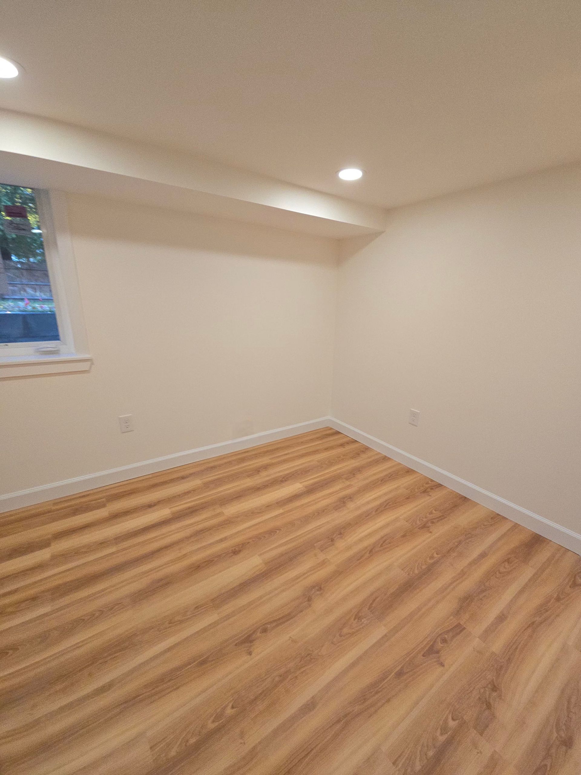 Newly added basement bedroom with neutral paint, white trim, and natural light.