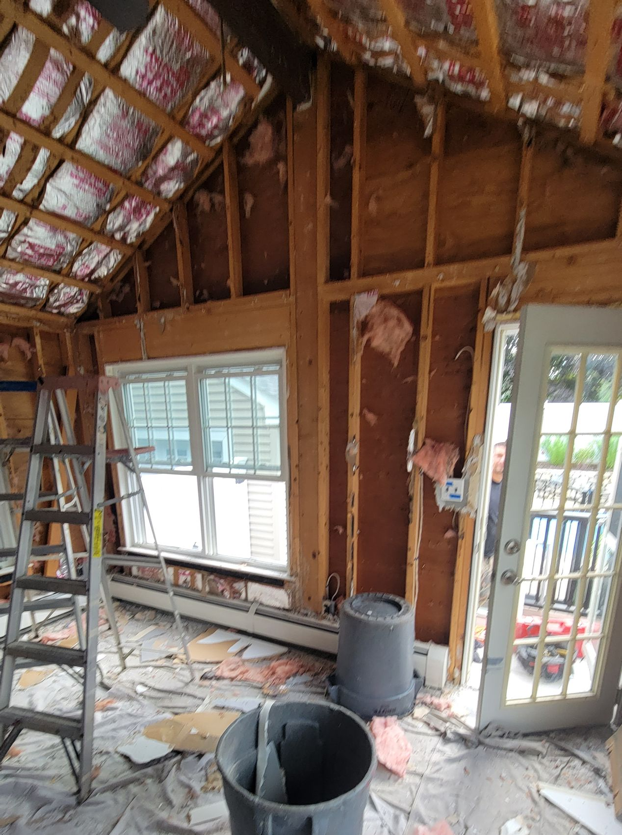Family room under renovation in Melrose MA with walls open to studs and insulation during remodeling