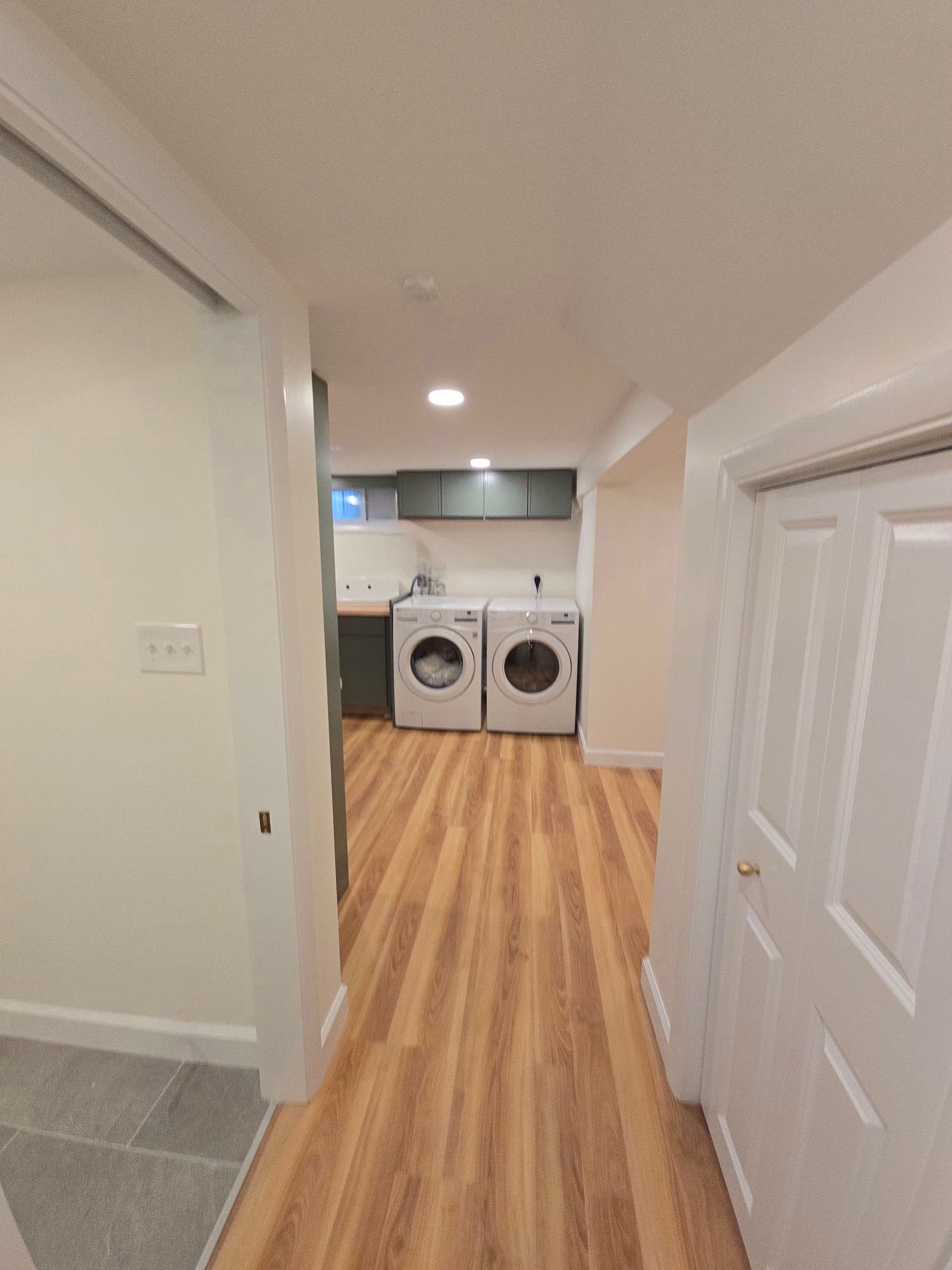 Finished basement laundry room with sage green cabinets and butcher block counters.