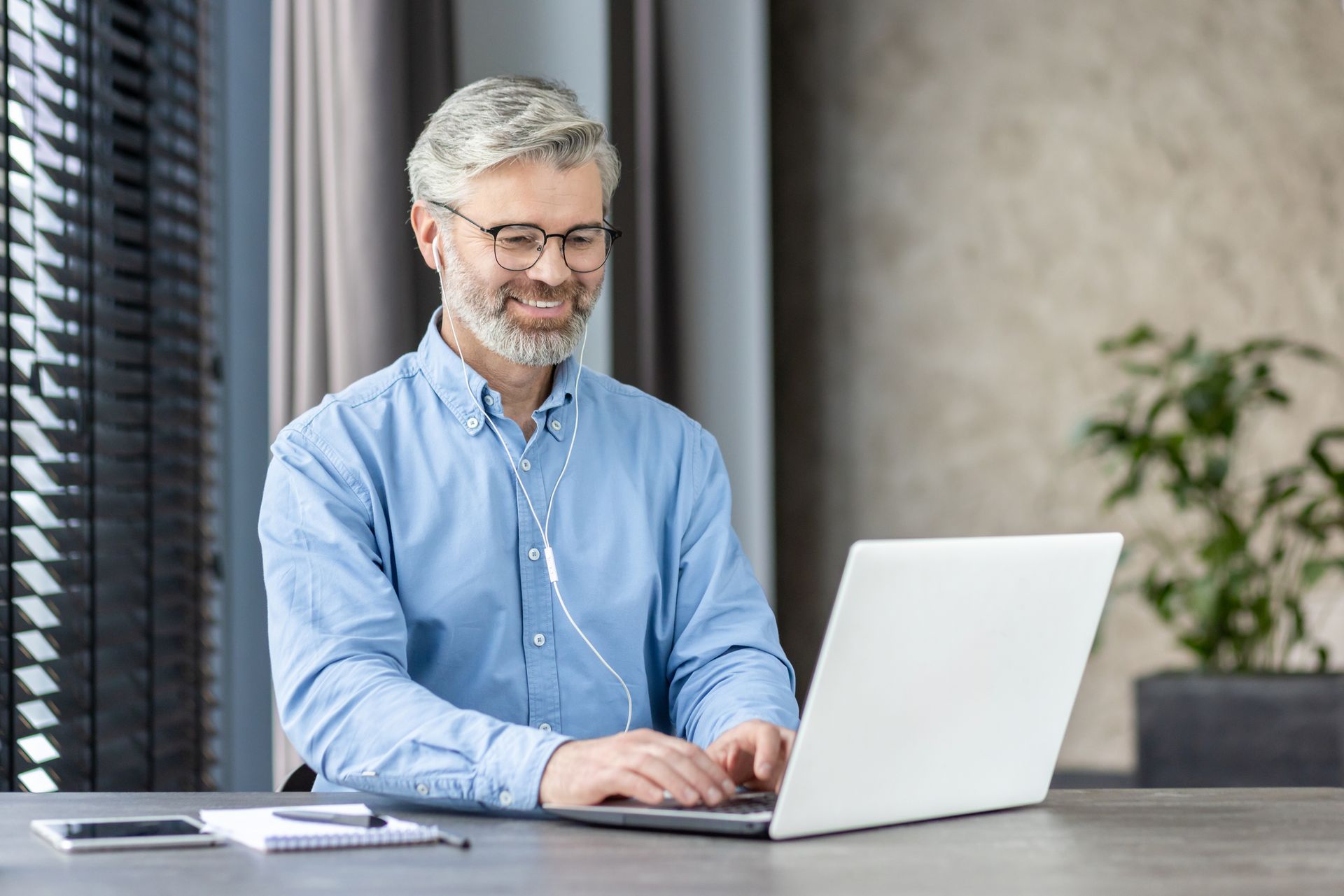 Smiling mature businessman using a laptop for remote work or online communication.