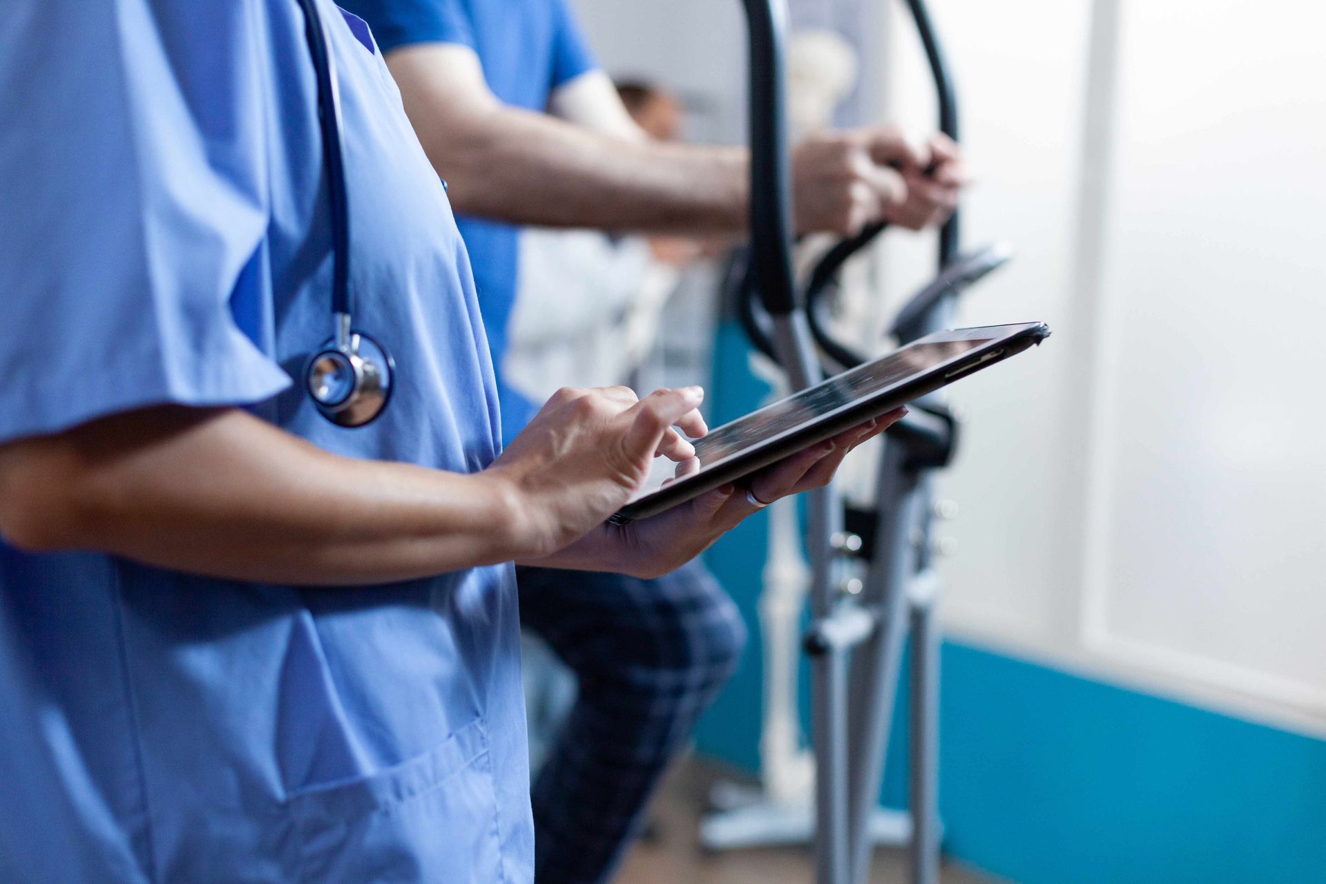 Assistant holding a gadget with a touch screen for physical exercise and physiotherapy. Assistant holding a gadget with a touch screen for physical exercise and physiotherapy.