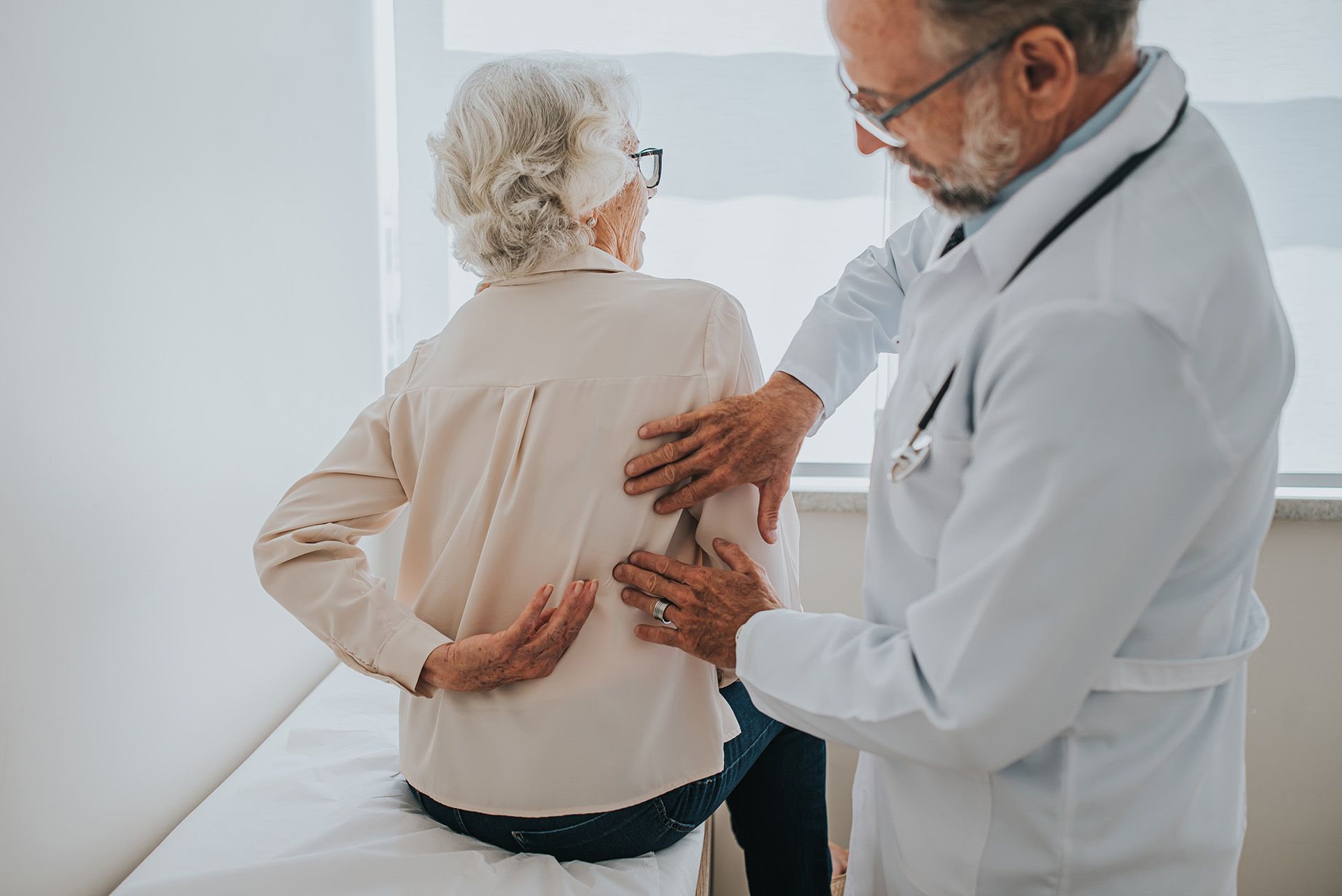 A senior patient with back pain is being treated by a pain management physician. A senior patient with back pain is being treated by a pain management physician.