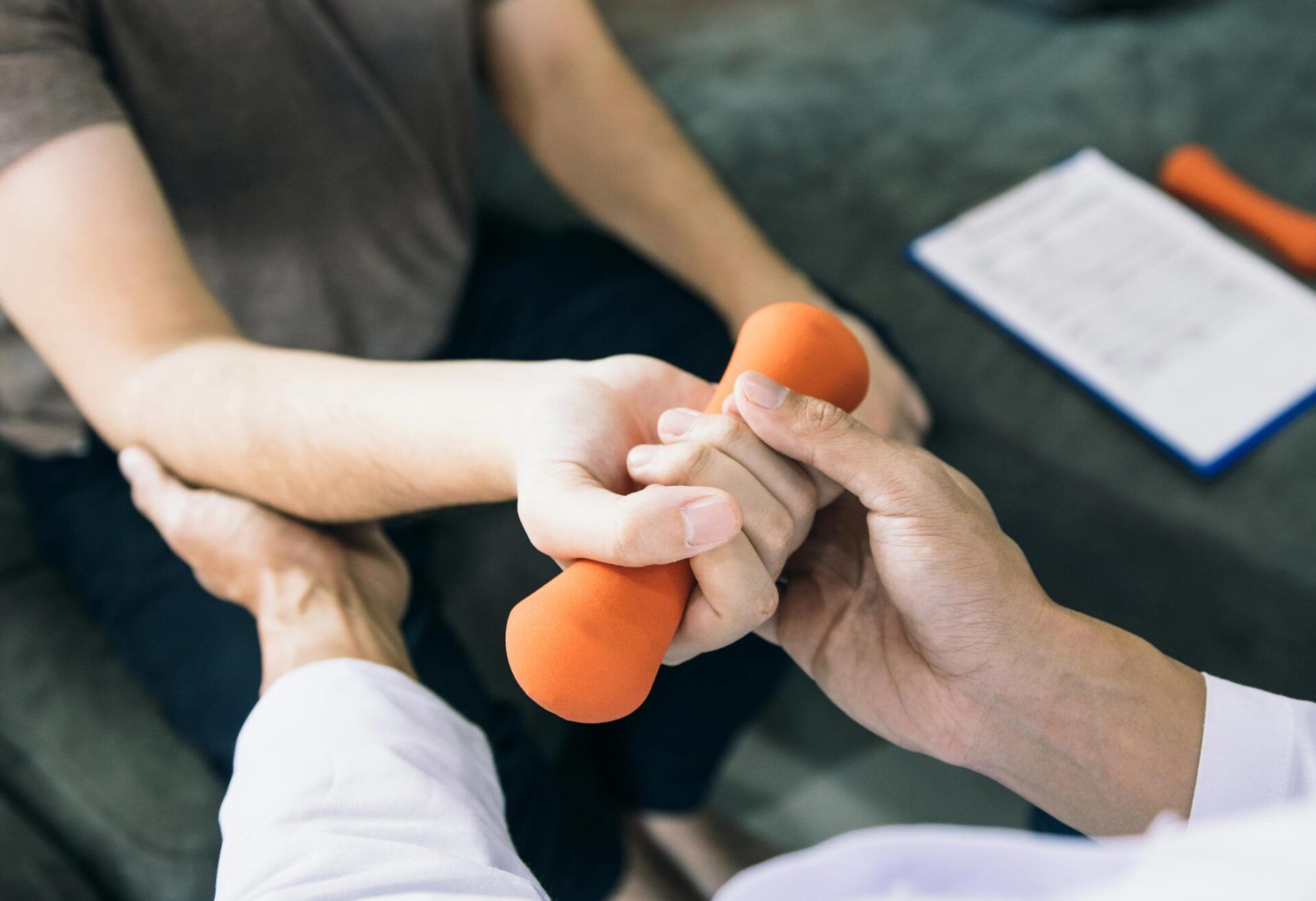 A doctor guides a patient's arm with orange dumbbell for exercise.