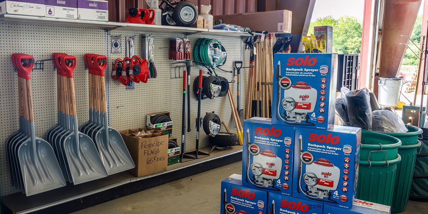 Hardware store interior with shovels, sprayers, and tools on display.