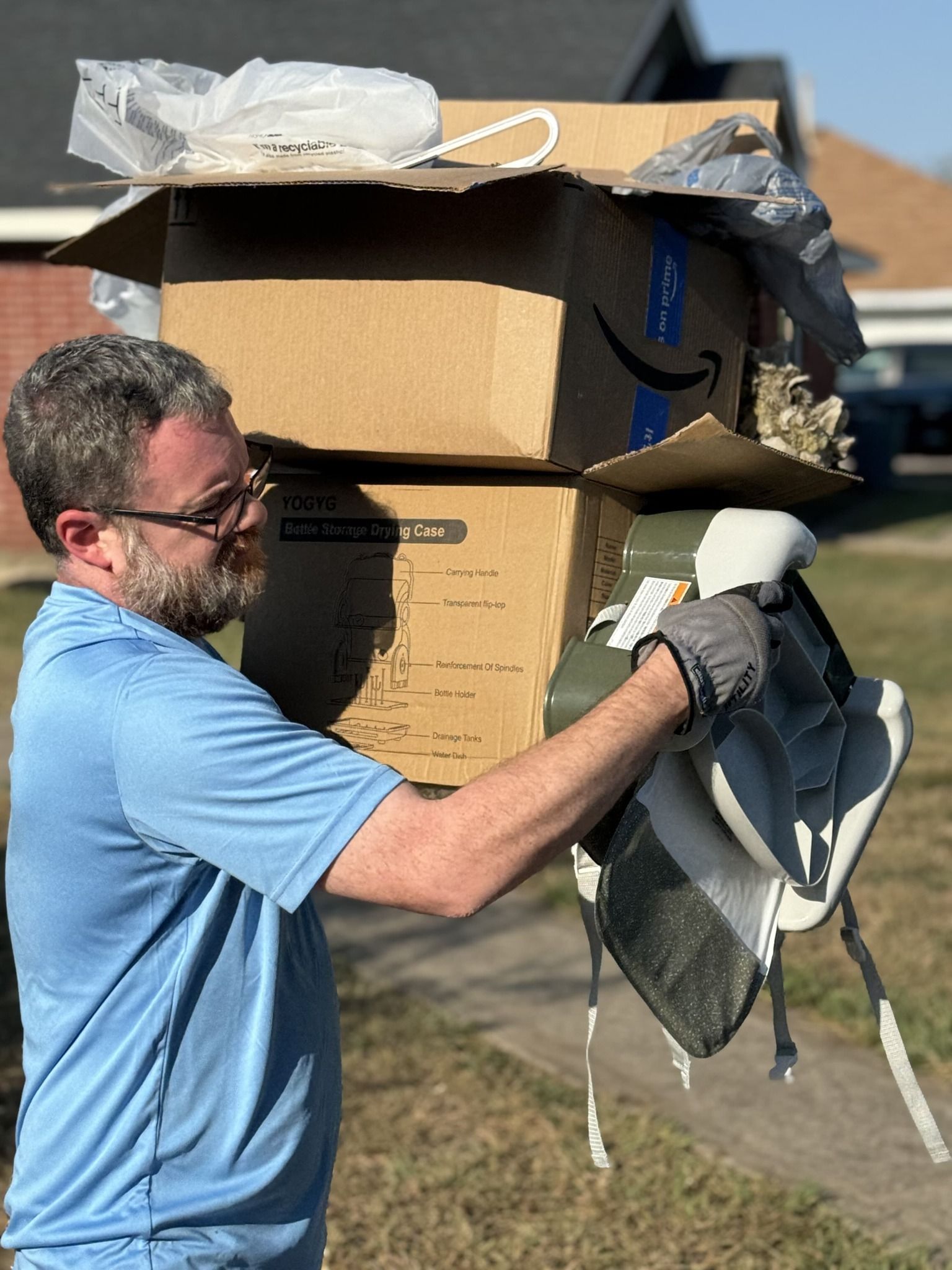 A man is carrying a stack of cardboard boxes on his head.