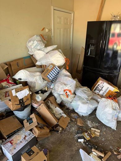 A room filled with lots of boxes and bags next to a refrigerator.
