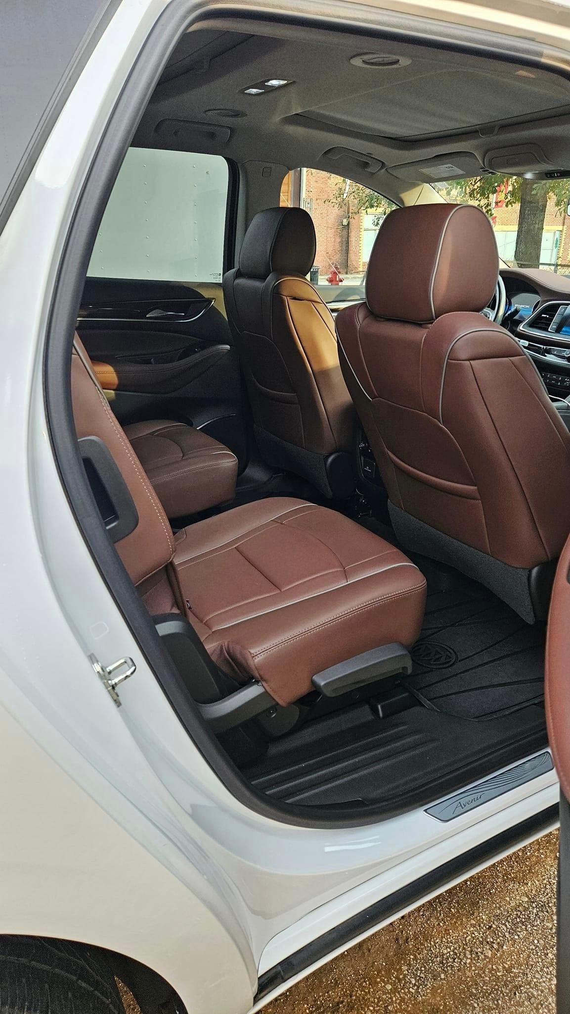 The back seat of a white suv with brown leather seats.