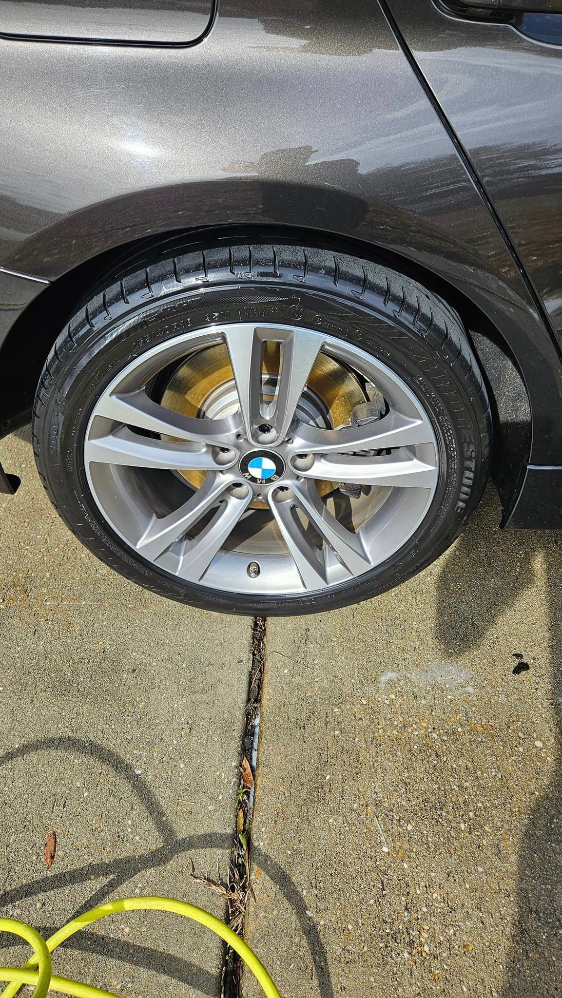 A close up of a car wheel on a sidewalk.