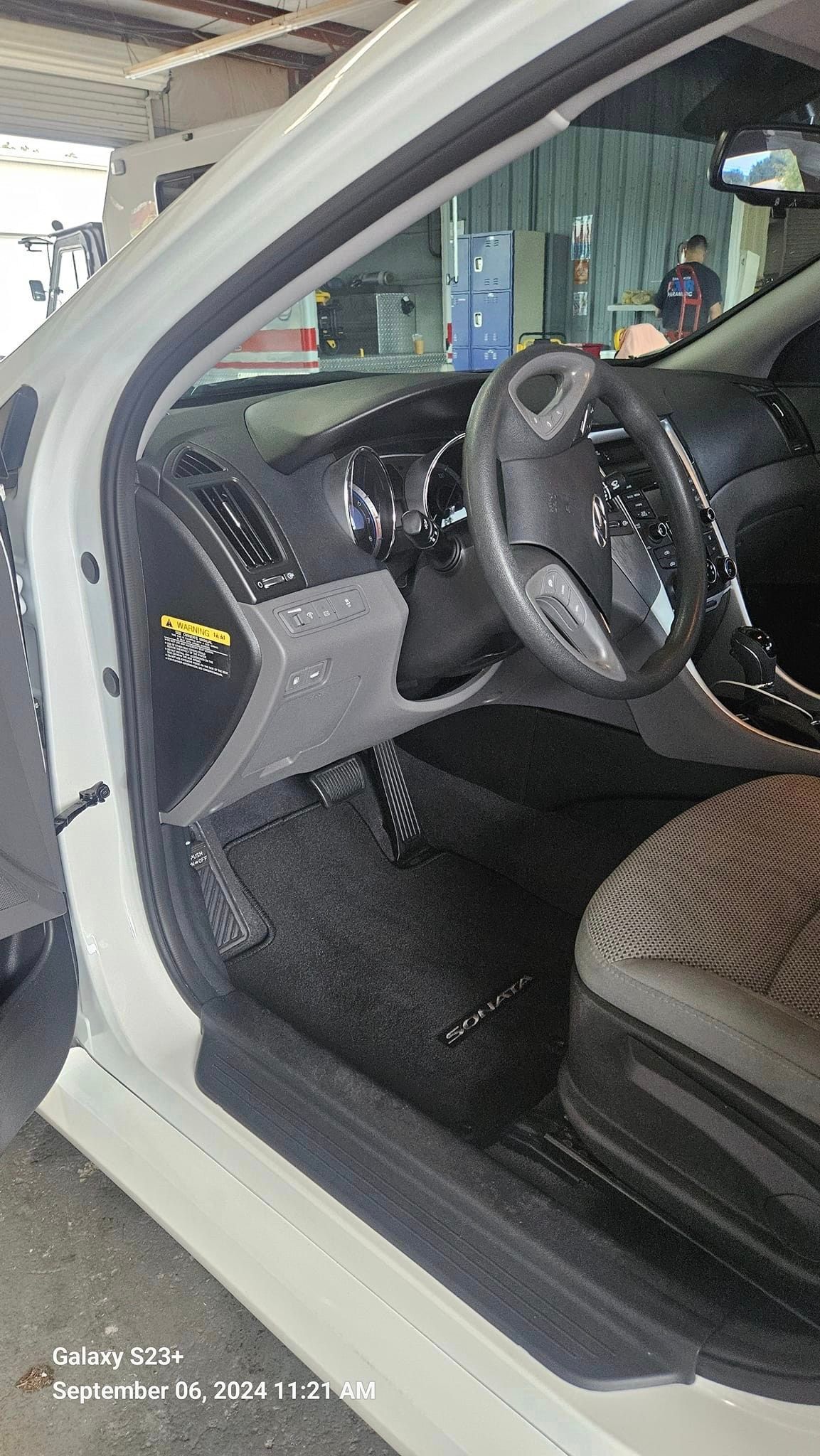 The inside of a white car with the door open and the steering wheel visible.
