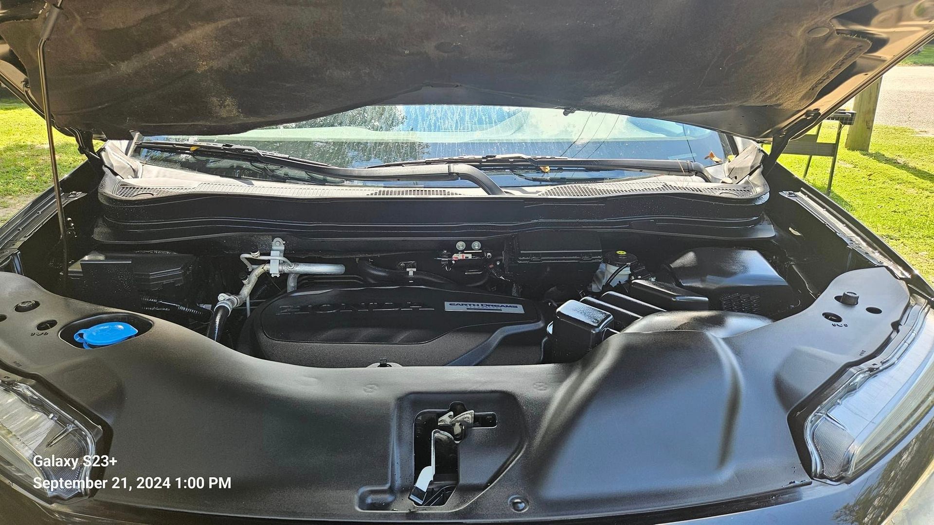 The hood of a black car is open and the engine is visible