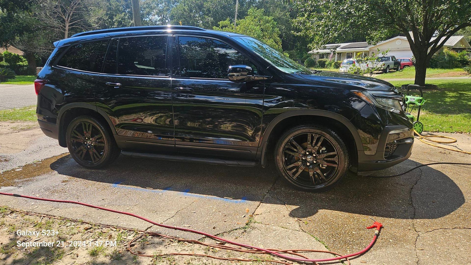 A black suv is parked in a driveway next to a hose.