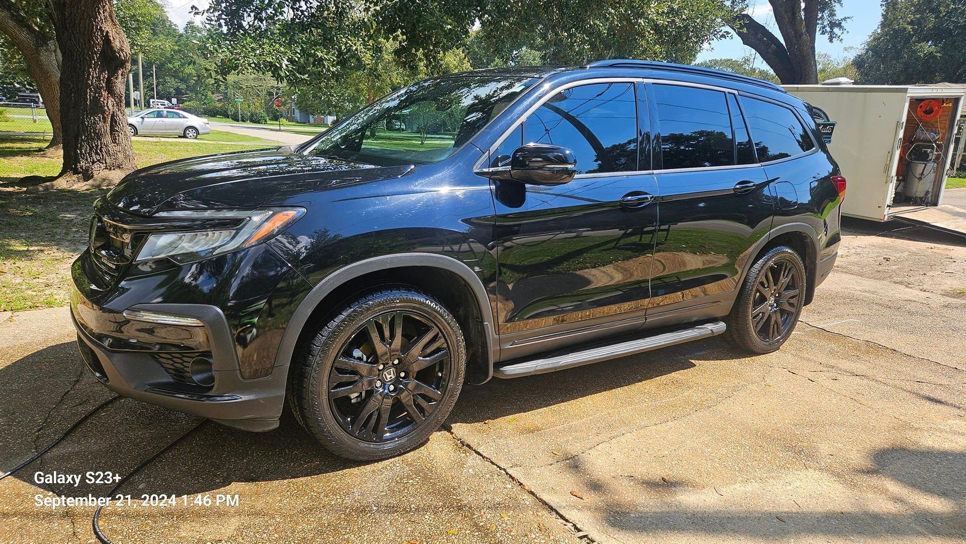 A black honda pilot is parked on the side of the road.