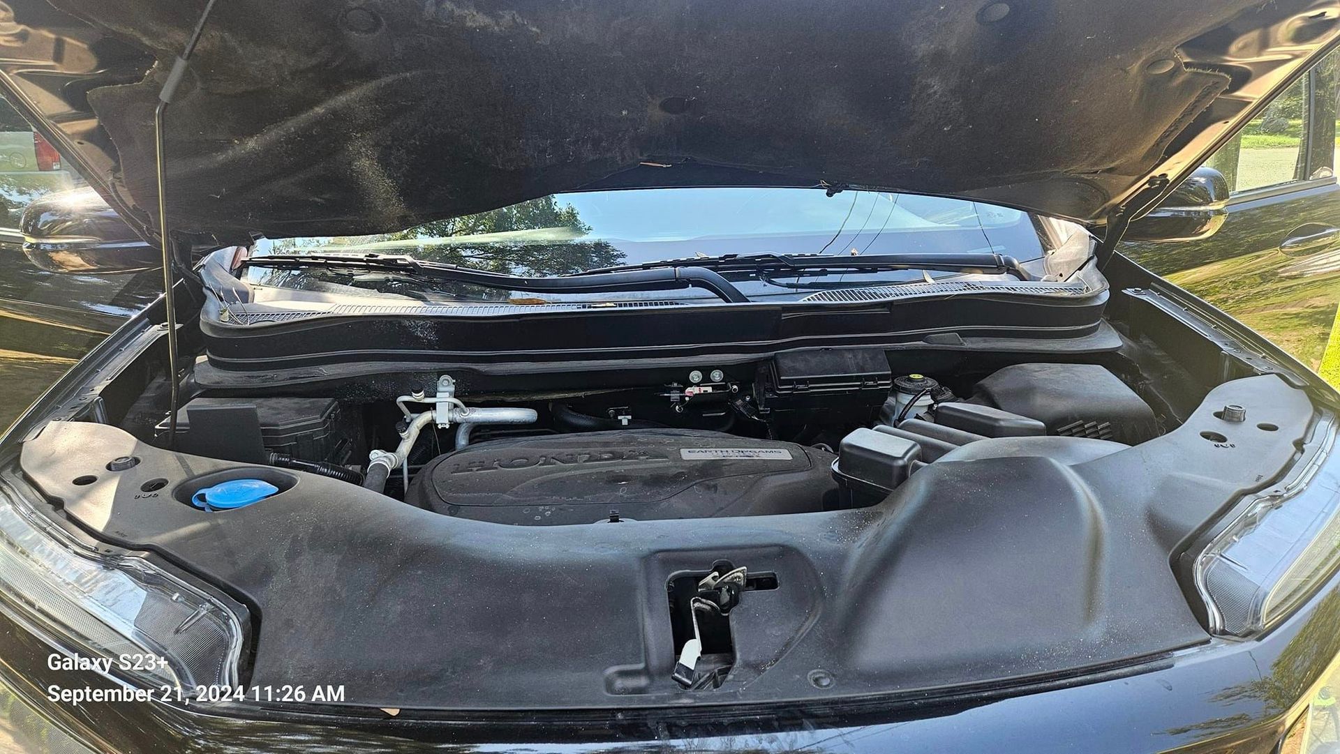 The hood of a black car is open and the engine is visible