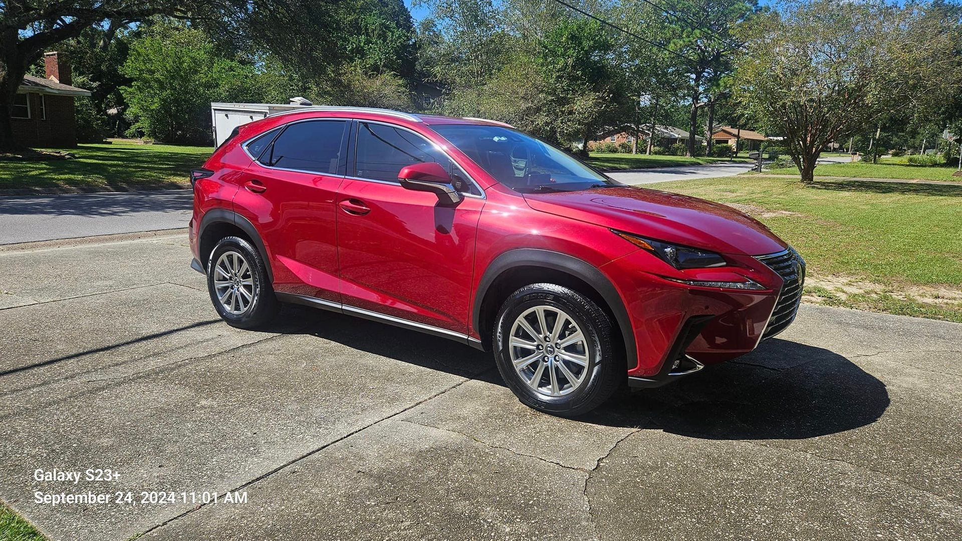 A red lexus nx is parked on the side of the road.