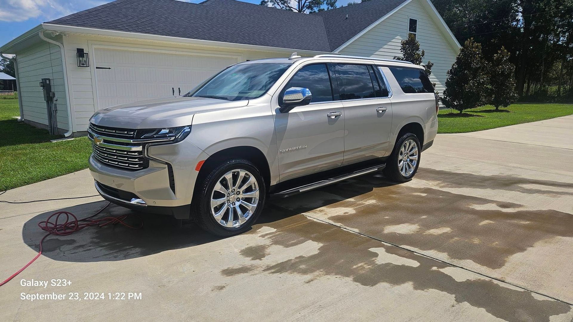 A silver suv is parked in a driveway in front of a house.