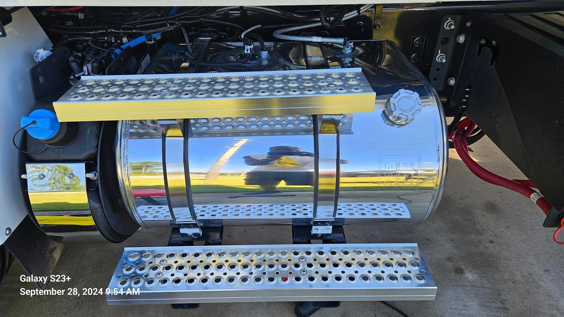 A stainless steel tank is attached to the side of a truck.