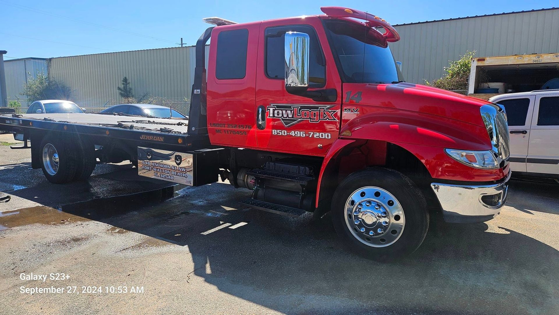 A red tow truck is parked in a parking lot.