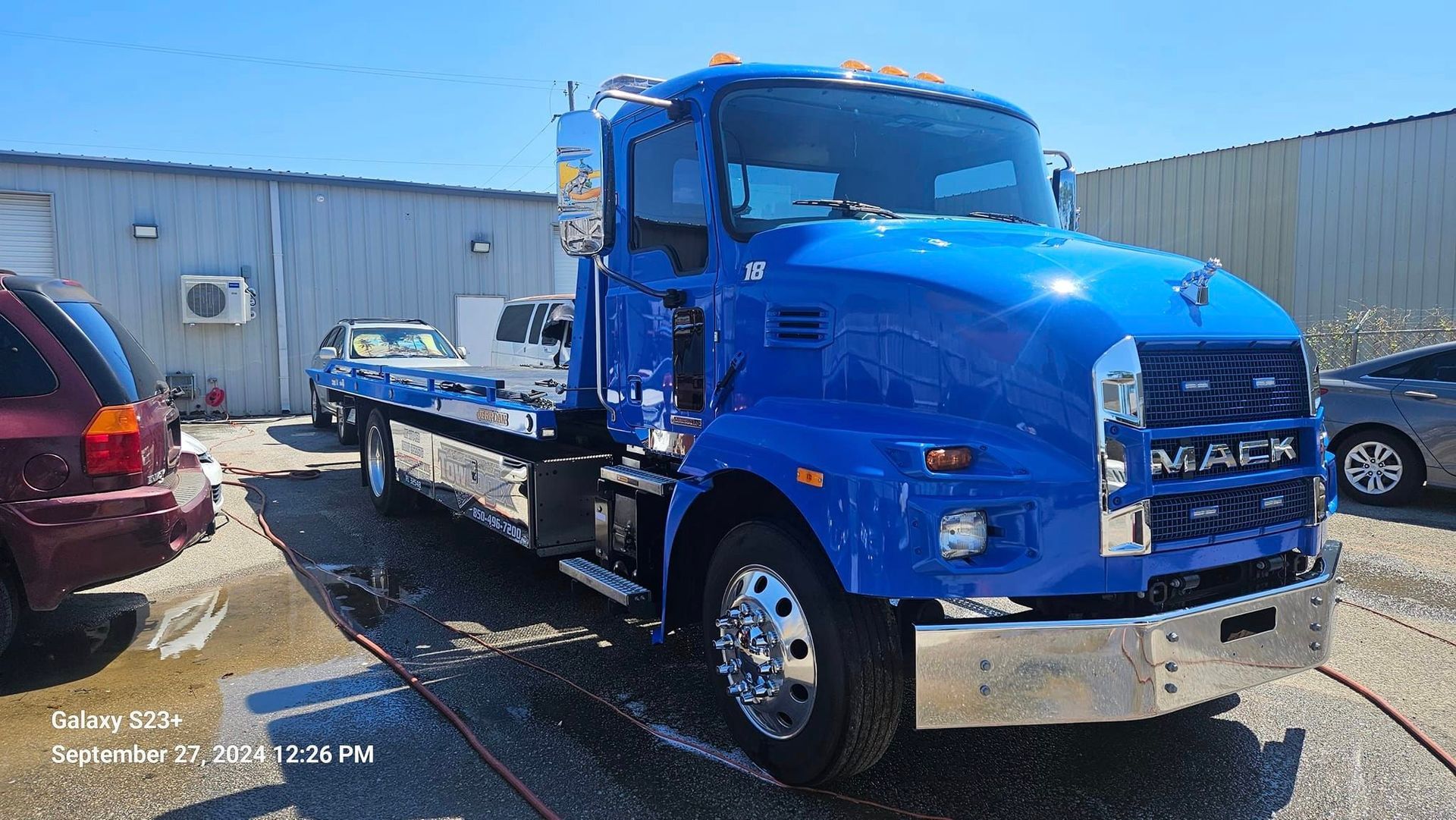 A blue tow truck is parked in front of a building.