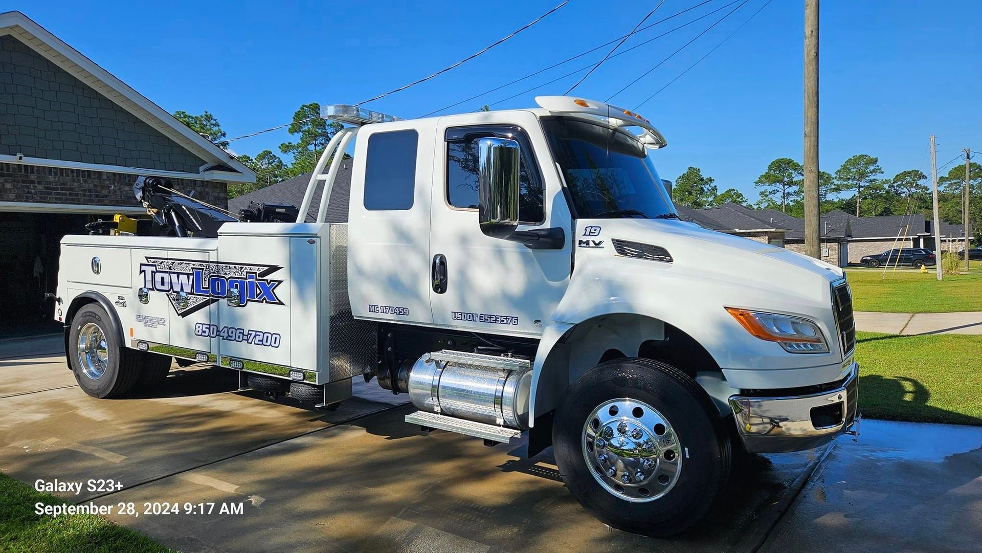 A white tow truck is parked in front of a house.