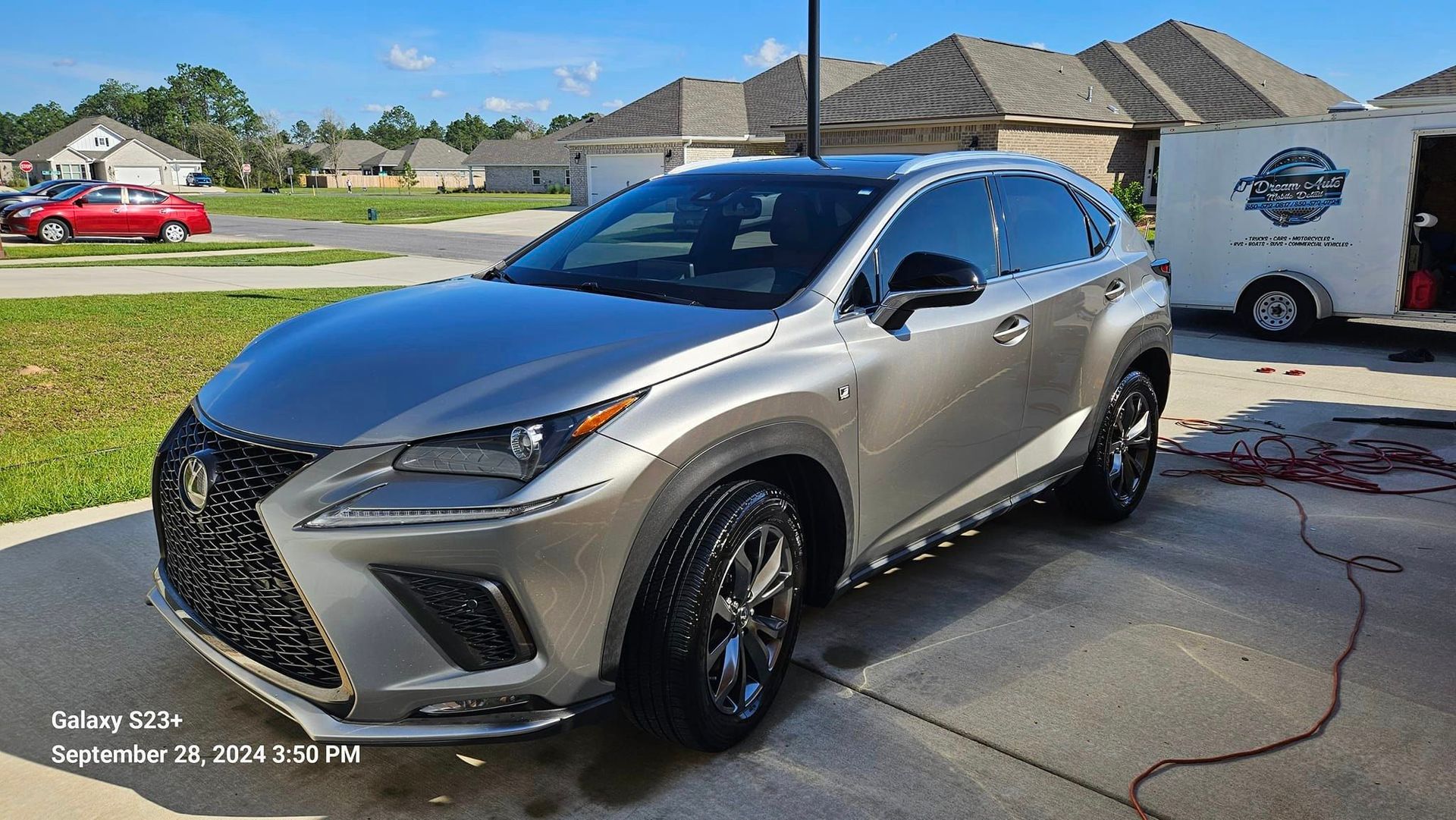 A silver lexus nx is parked in a driveway in front of a house.