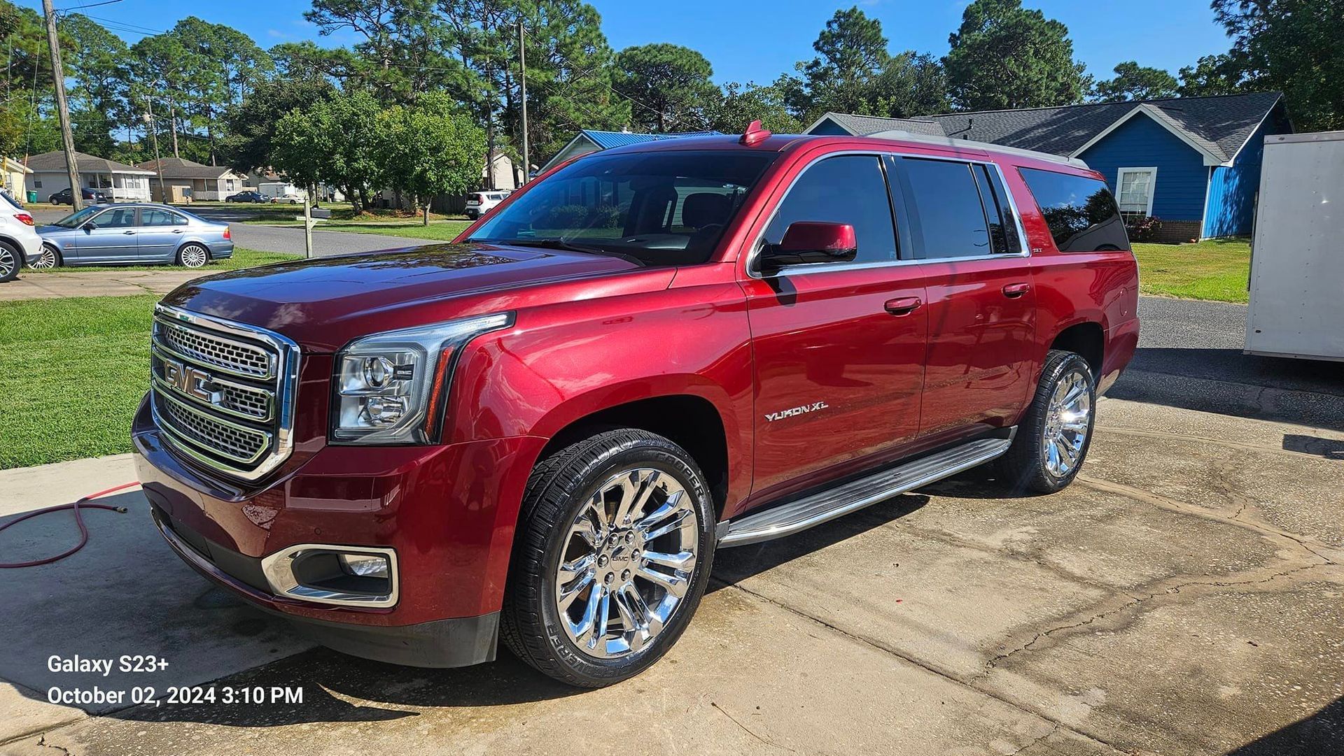 A red gmc yukon is parked on the side of the road.